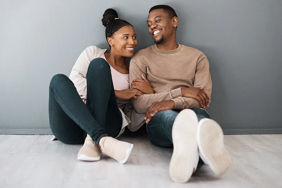Joyful couple sitting on the floor together smiling. Achieve hormone balance with Maven Wellness's bioidentical hormone therapy in San Diego.