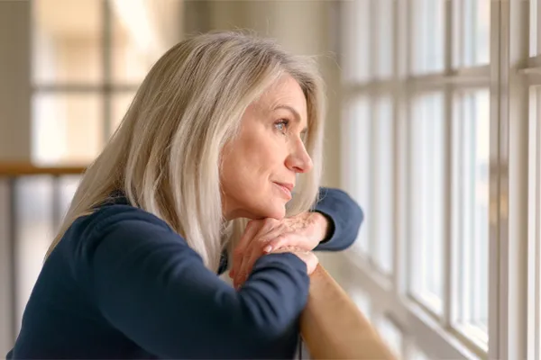 Brain-Fog-Clinic A thoughtful woman gazes out a window, symbolizing the mental fatigue and distraction often associated with brain fog. Get root-cause brain fog treatment by Dr. Noelani Rodriguez in San Diego.