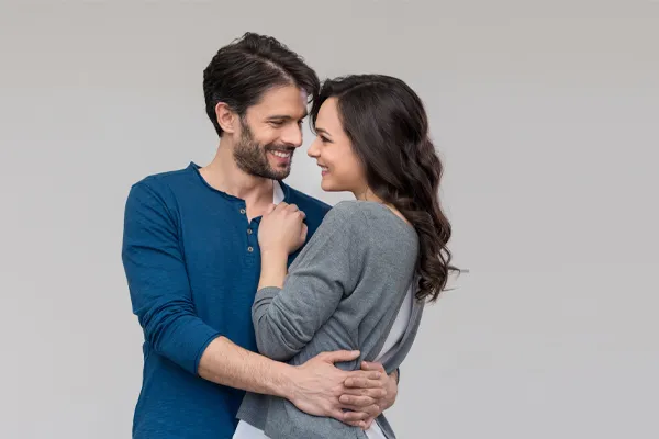 Erectile-Dysfunction-Doctor A man in a blue shirt embracing a woman in a gray shirt smiles due to his successful erectile dysfunction care from Dr. Noelani Rodriguez in San Diego.
