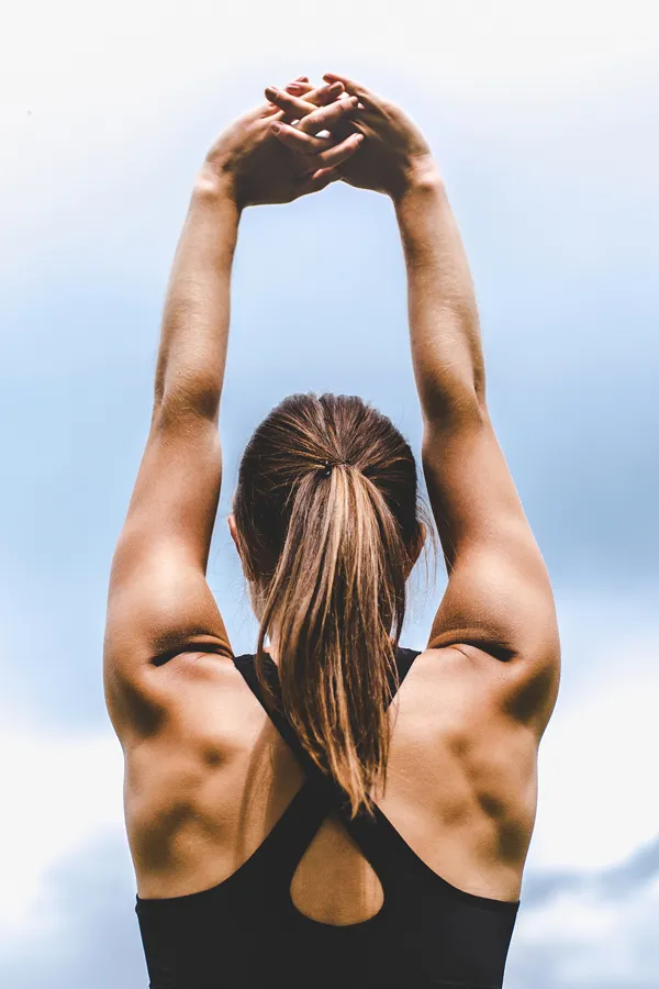 GLP-1-Weight-Loss-Injections-Treatment Back view of a woman stretching toward the sky, symbolizing empowerment and body transformation through GLP-1 weight loss treatments by Dr. Noelani Rodriguez in San Diego.