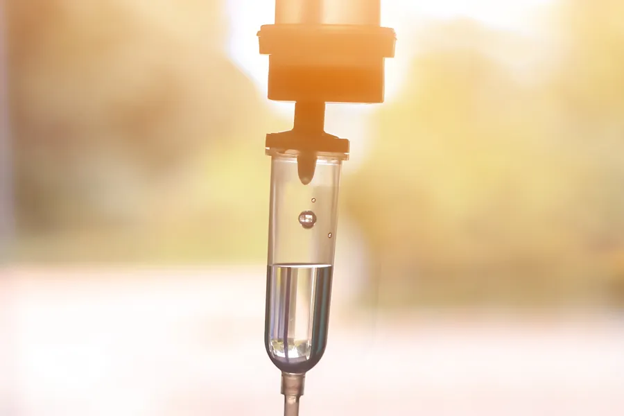 Close up of an IV drip against a sunlit background. Receive personalized IV therapy treatments by Maven Wellness in San Diego.
