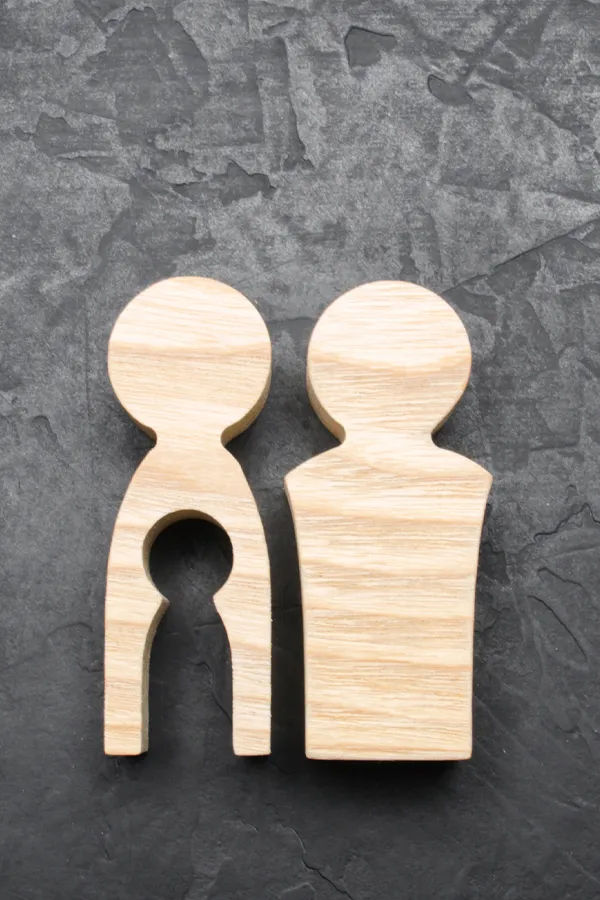 Infertility-Treatment Woodcut figures of a man and woman with a child-shaped area cut out from the woman figure. Get treatment for infertility from Dr. Noelani Rodriguez in San Diego.