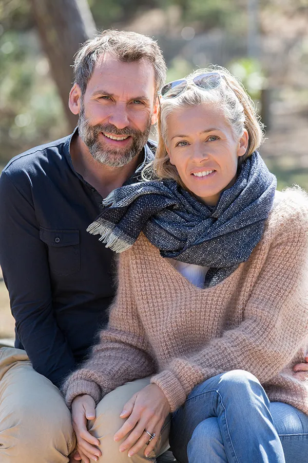 Inflammotory-Bowel-Disease-IBD-Treatment Happy middle-aged couple outdoors wearing cozy fall clothes, smiling calmly. Dr. Noelani Rodriguez is a compassionate IBD specialist in San Diego supporting long-term gut health and symptom relief through functional medicine.