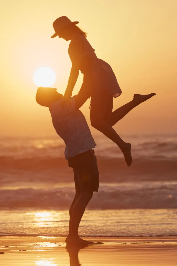 LCL-Tears-Treatment A man lifts a woman into the air on the beach. Get treatment for LCL tears from Dr. Noelani Rodriguez in San Diego.