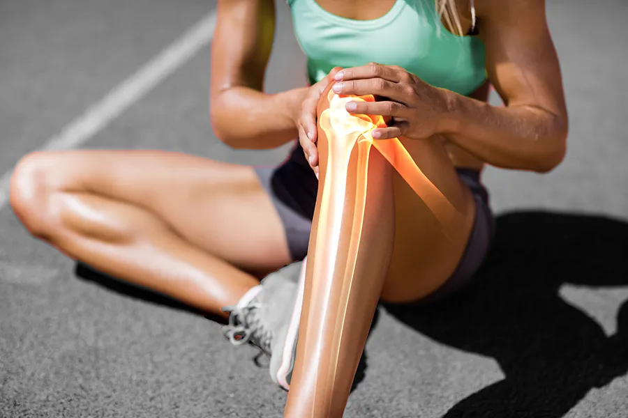 MCL-Tears-Clinic A female runner sits on the track and holds her knee in pain. Schedule treatment for MCL tears from Dr. Noelani Rodriguez in San Diego.