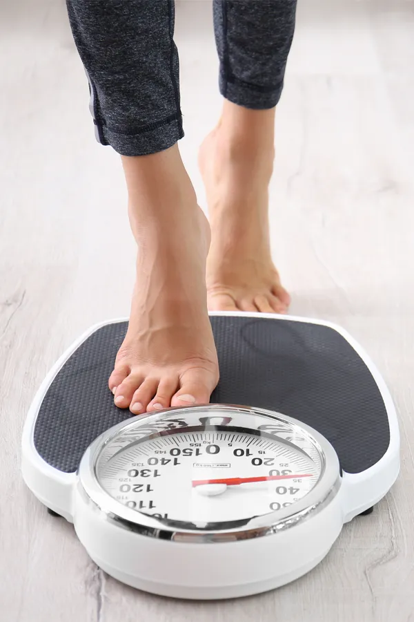 Obesity-Treatment Close up of feet stepping onto a scale. Receive expert functional medicine for obesity treatment by Dr. Noelani Rodriguez in San Diego.