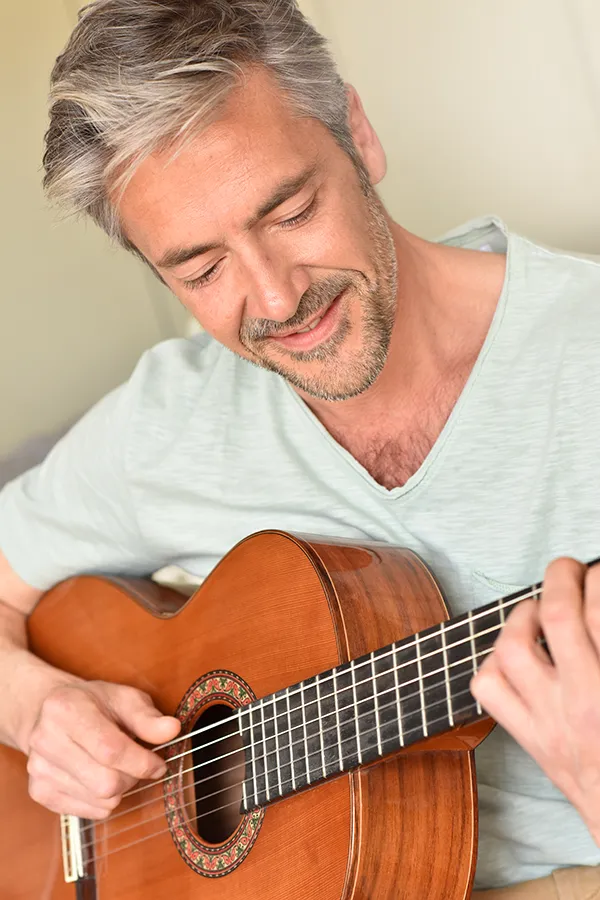 Osteoarthritis-Treatment A middle-aged man happily plays guitar. Get osteoarthritis treatment from Dr. Noelani Rodriguez in San Diego.