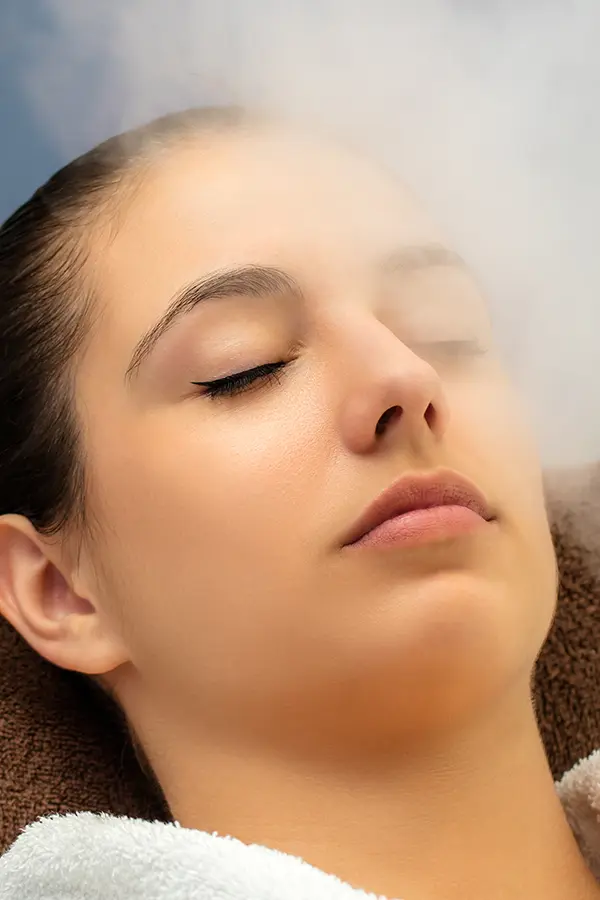 Ozone-Therapy-Treatment Close-up of a woman with her eyes closed breathing in mist. Get ozone therapy from Dr. Noelani Rodriguez in San Diego.