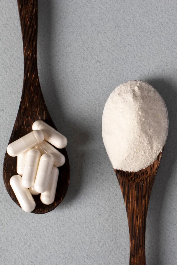Peptide-Therapy-Treatment Two wooden spoons on a table, on with white powder and one with capsules, representing peptide therapy from Dr. Noelani Rodriguez in San Diego.
