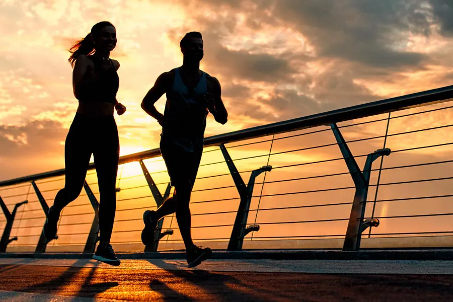 Performance-Enhancing-Peptides-Doctor A couple jogging on a bridge at sunrise, representing performance enhancing peptide therapy from Dr. Noelani Rodriguez in San Diego.