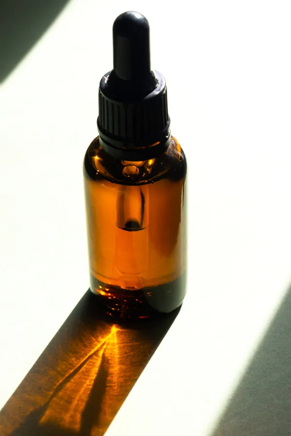 Performance-Enhancing-Peptides-Treatment A brown dropper bottle on a table lit by sunlight, representing performance enhancing peptide treatment from Dr. Noelani Rodriguez in San Diego.