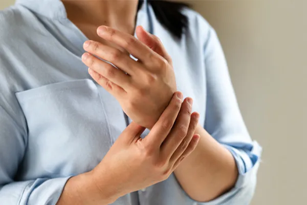 Rheumatoid-Arthritis-Clinic Close up of a woman in a blue blouse rubbing her wrist. Get rheumatoid arthritis treatment from Dr. Noelani Rodriguez in San Diego.