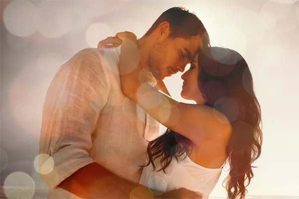 Sexual-Wellness-for-Women-and-Men-Doctor A couple in linen shirts standing in a sparkling light embraces each other with their foreheads touching and eyes closed, happy with their sexual wellness treatments from Dr. Noelani Rodriguez in San Diego.