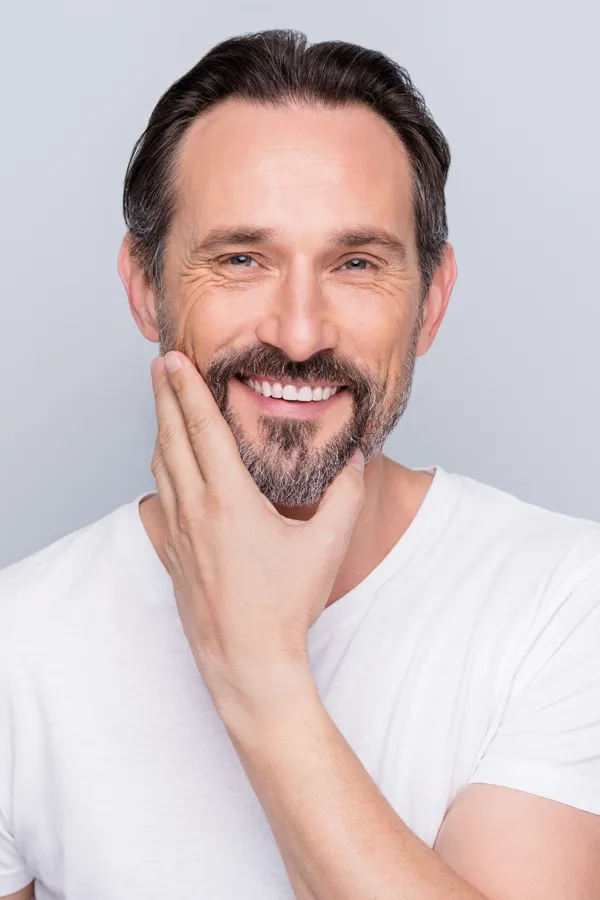 Sjogrens-Syndrome-Treatment Middle-aged man touching his cheek and smiling confidently after finding relief with functional medicine for sjogren's syndrome offered by Dr. Noelani Rodriguez in San Diego.