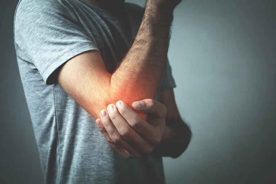 Tennis-Elbow-Clinic A man holds his elbow in pain. Schedule tennis elbow treatment from Dr. Noelani Rodriguez in San Diego.