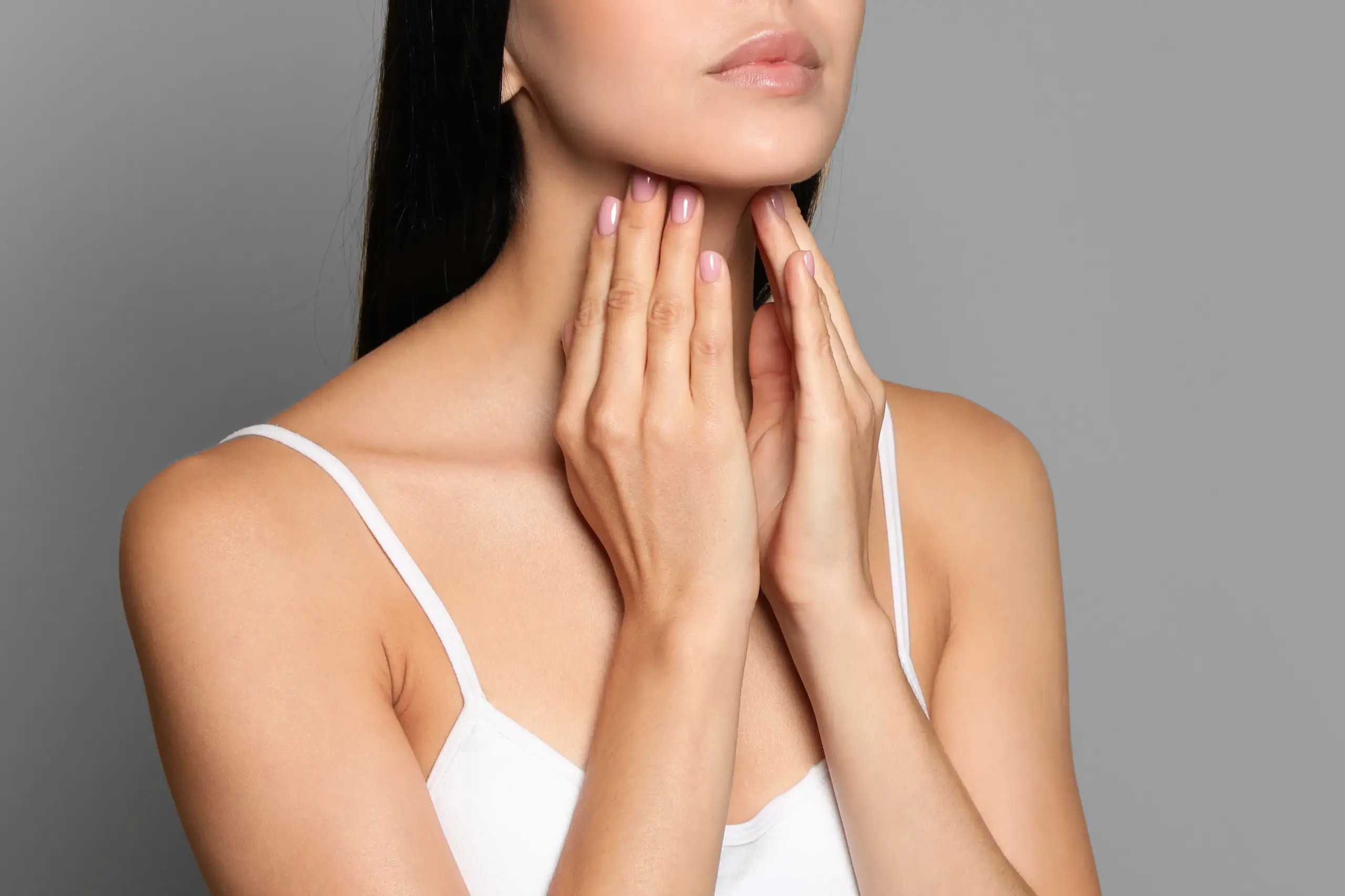 Thyroid-Doctor A woman in a white tank top touches her neck looking for signs of thyroid disorder. Get help for thyroid disorders from Dr. Noelani Rodriguez in San Diego.