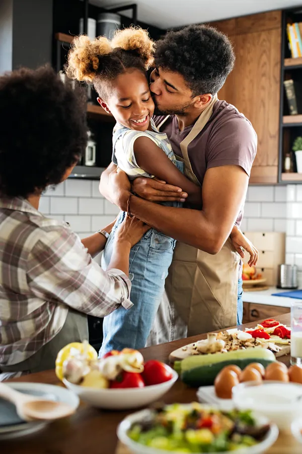 Type-2-Diabetes-Treatment Happy family of three smiling while cooking a healthy meal at home after receiving expert functional medicine for type 2 diabetes treatment by Dr. Noelani Rodriguez in San Diego.