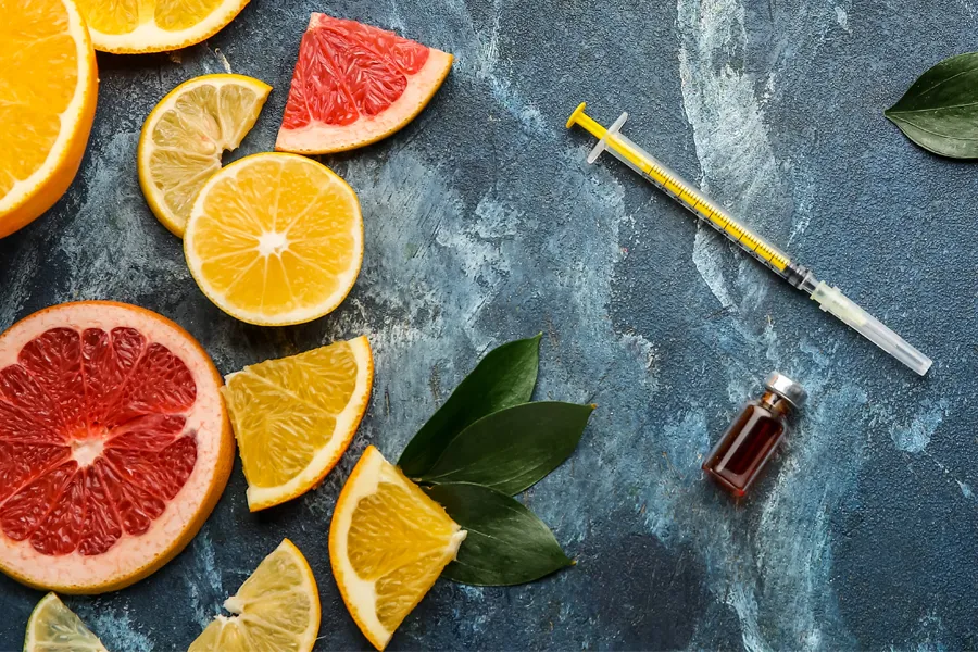 Vitamin-Injection-Doctor A gray marble countertop covered with sliced fruit and a syringe and vial, representing vitamin injections from Dr. Noelani Rodriguez in San Diego.